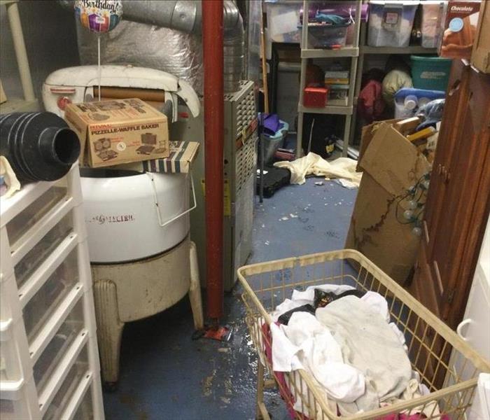 Utility room with boxes and shelves with items by wet floor