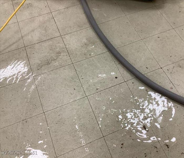 Standing water on a tile floor with industrial hose