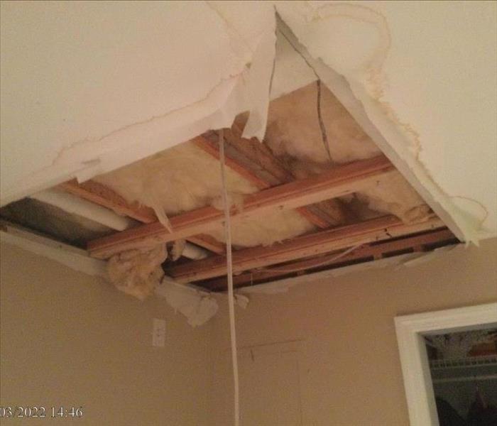 Open ceiling cavity with water stains, wet ceiling joists, and insulation