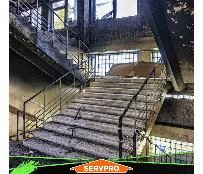 Flight of stairs in a building with charred ceiling and walls from fire damage.